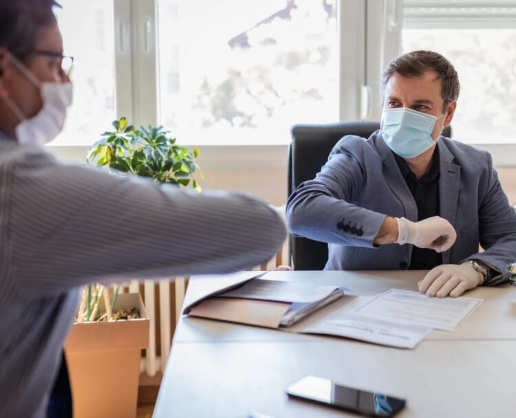 Two people sitting at a table wearing masks.