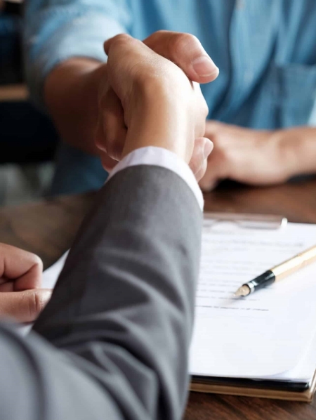 Two people shaking hands over a table.