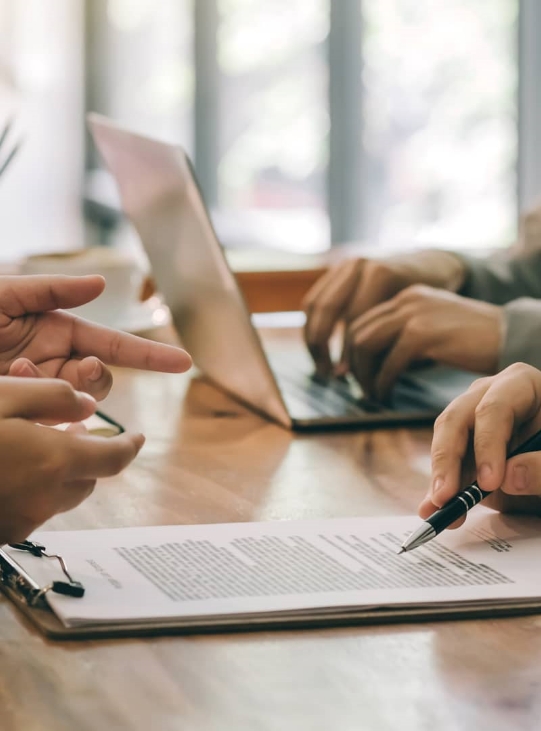 A group of people sitting around a table with papers.