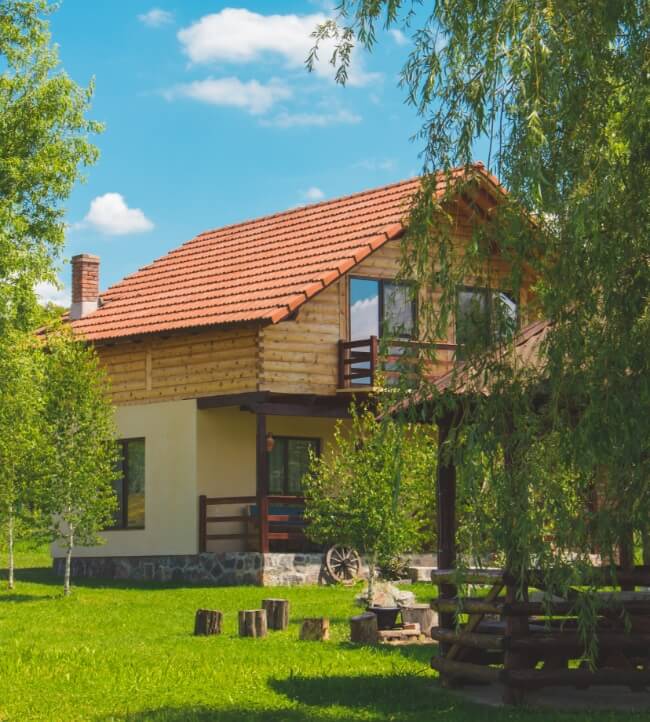 A house with a red roof sitting in the middle of a green field.