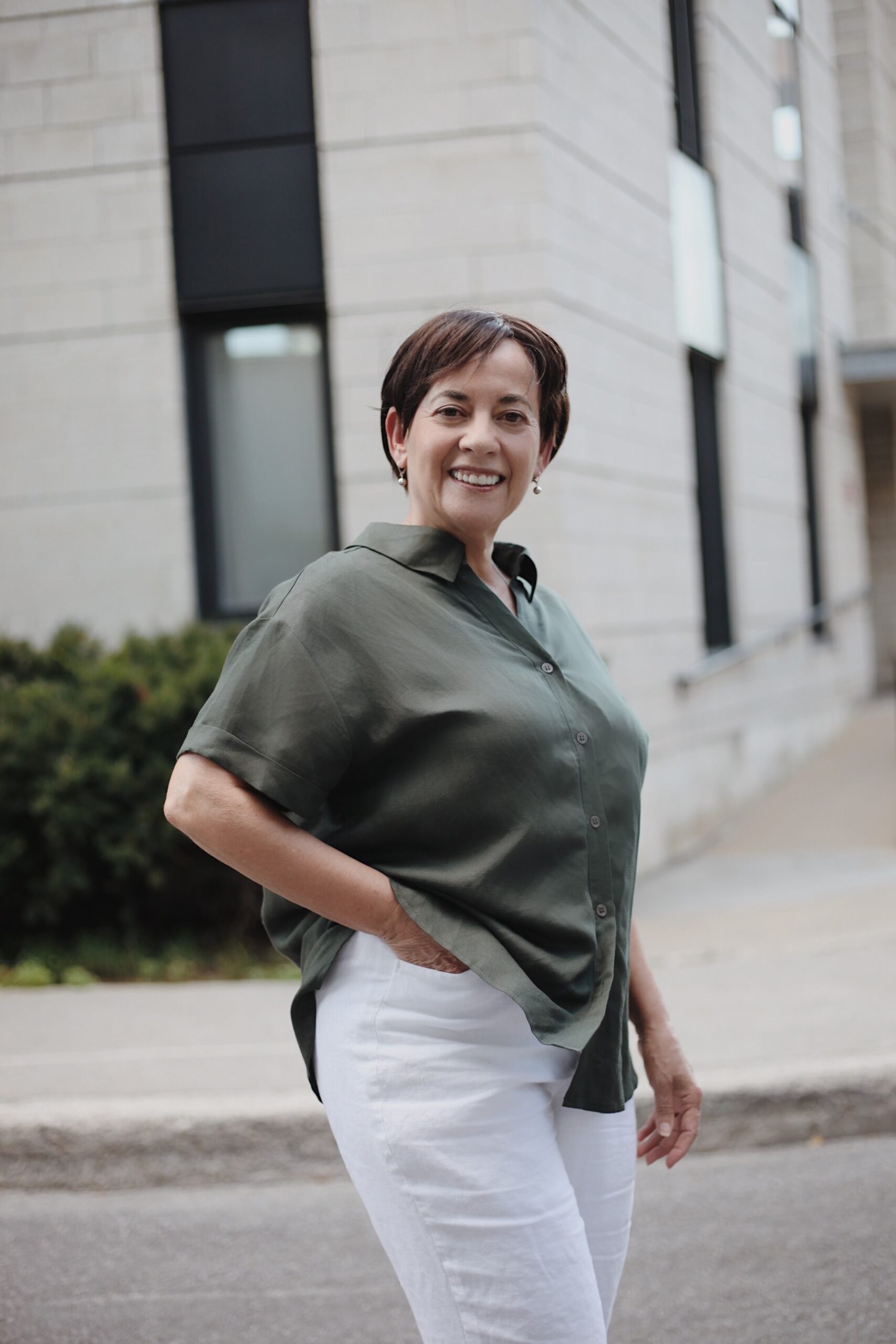 A woman standing on the sidewalk in front of a building.