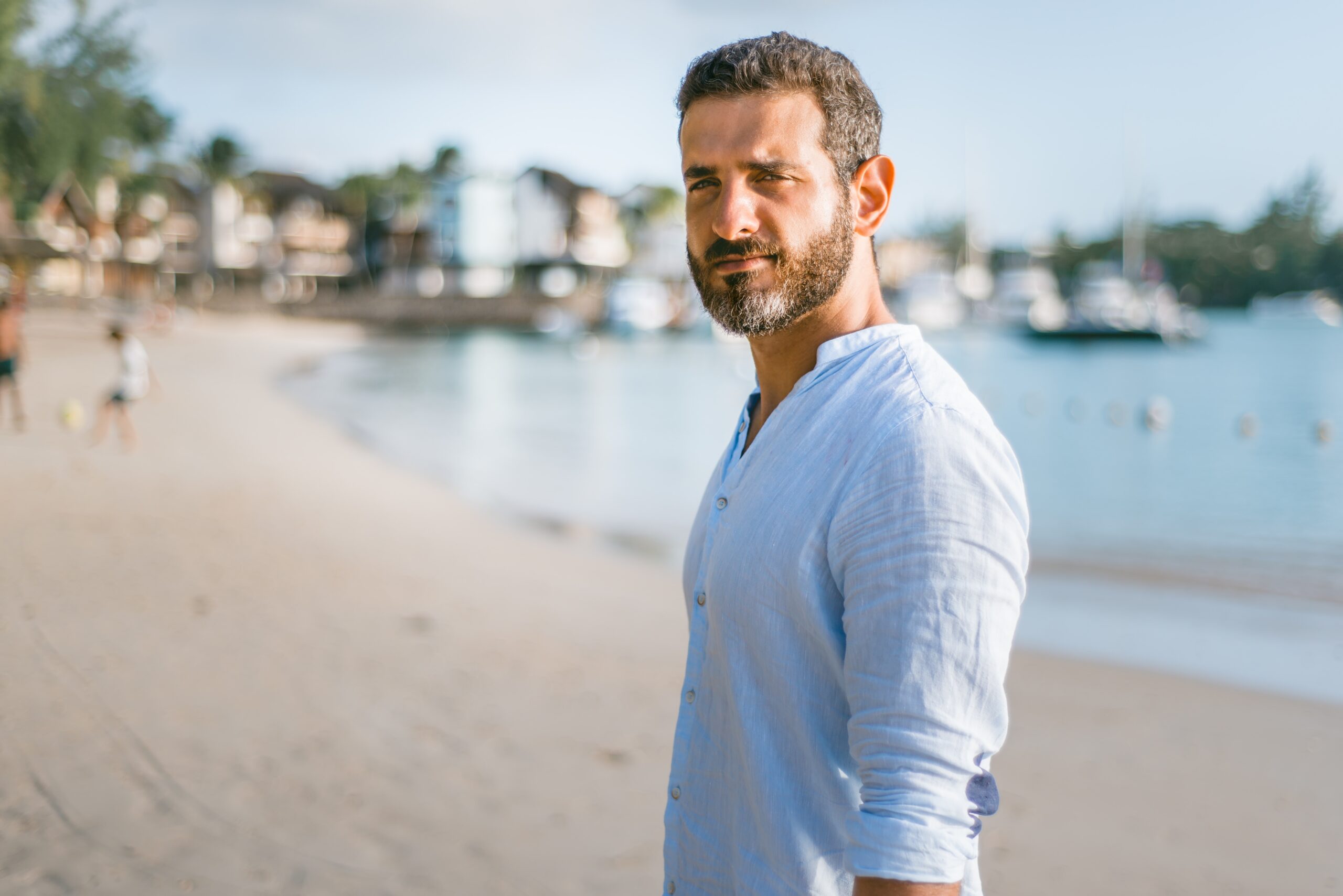 A man standing on the beach in front of some boats.